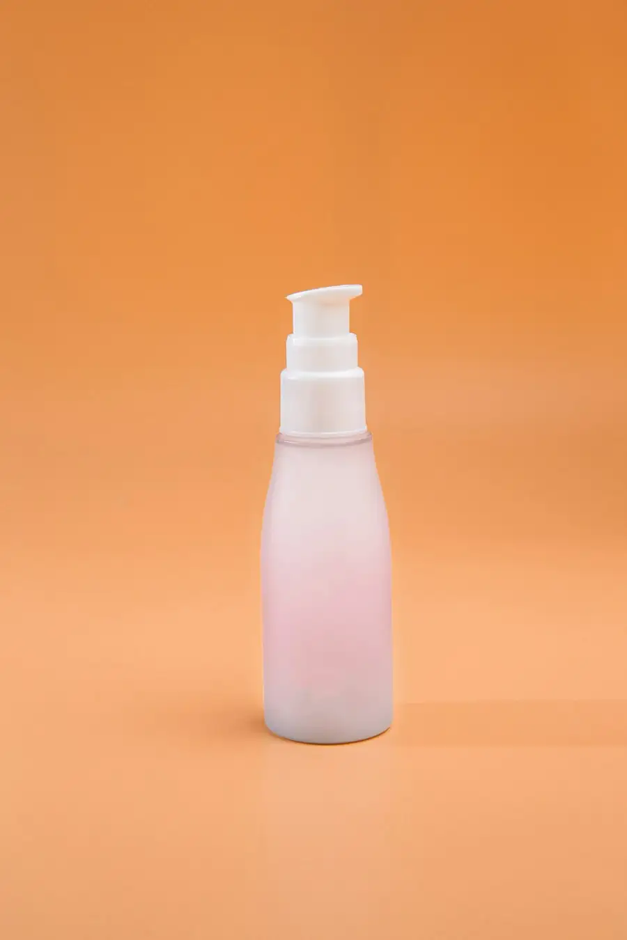 Frosted pump bottle standing on an orange background