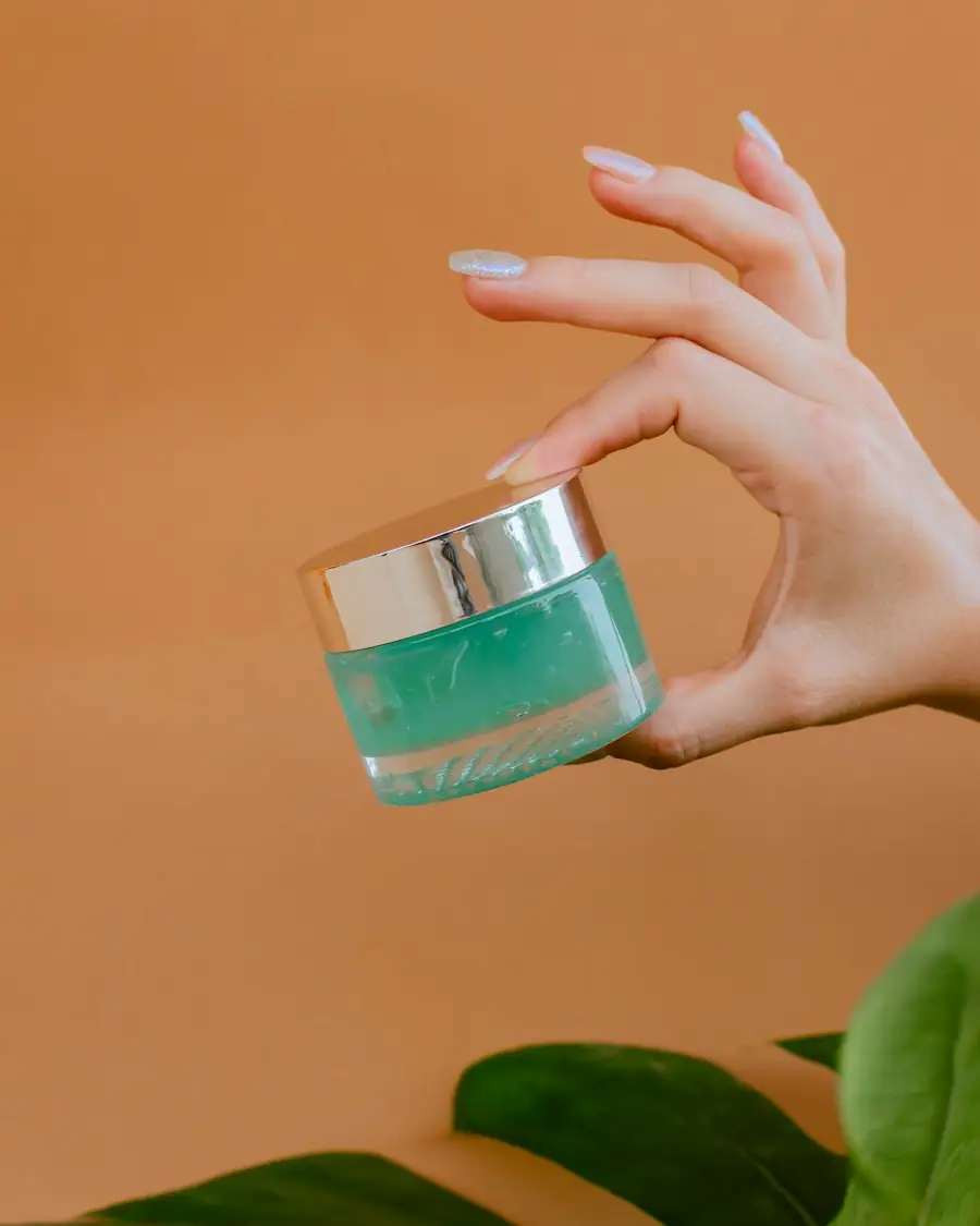 Hand holding a teal cream jar against an orange wall