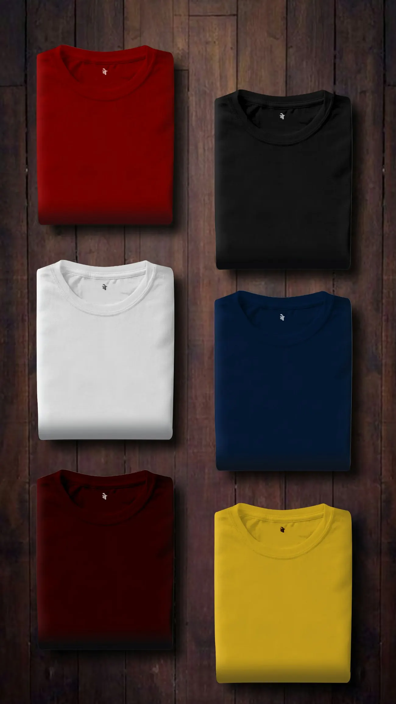 Folded t-shirts in six colours laid out on dark wood