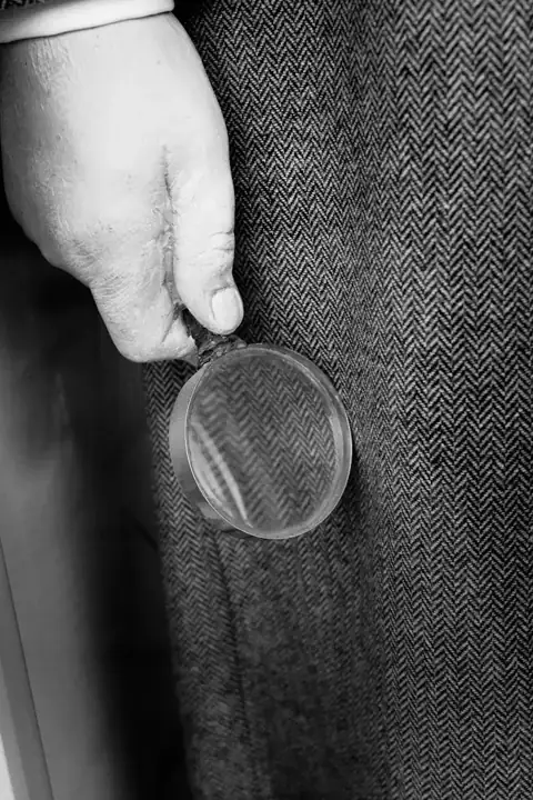 Inspector holding a magnifier against woven fabric