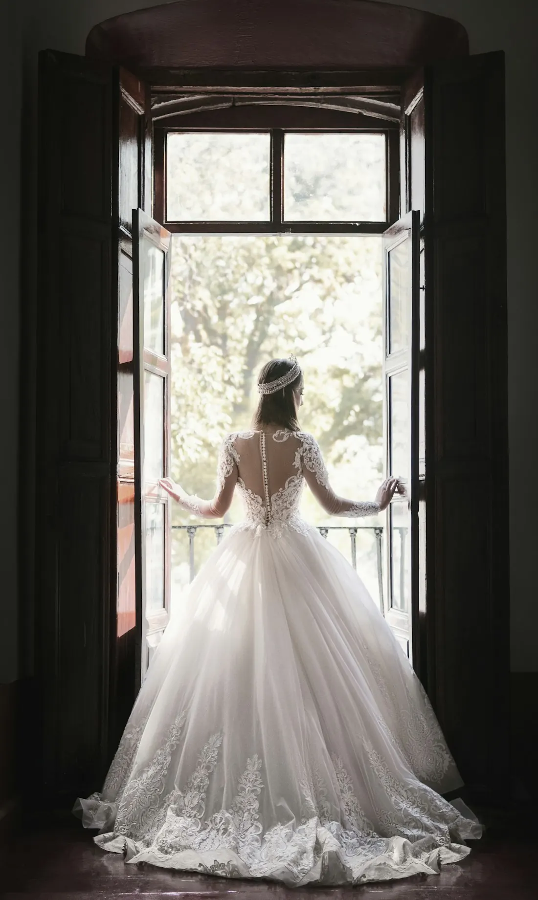 Bride in a full white gown standing at a tall window