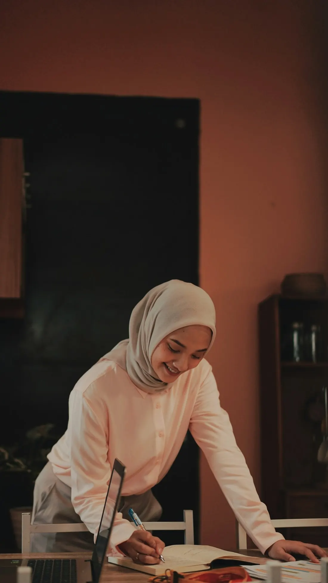 Designer in a white hijab sketching a collection at her desk