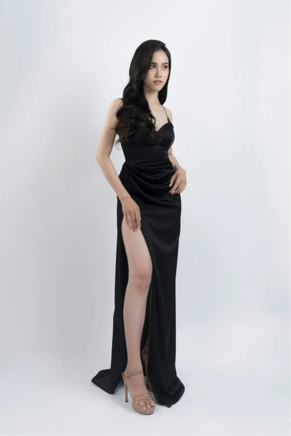 Model in a black satin evening gown with a high slit