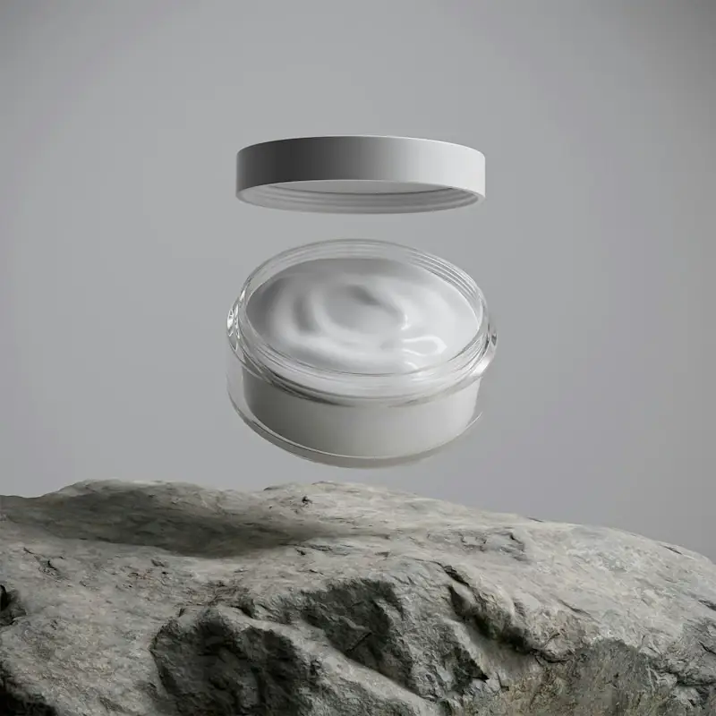 Open cream jar with its lid floating above a grey stone