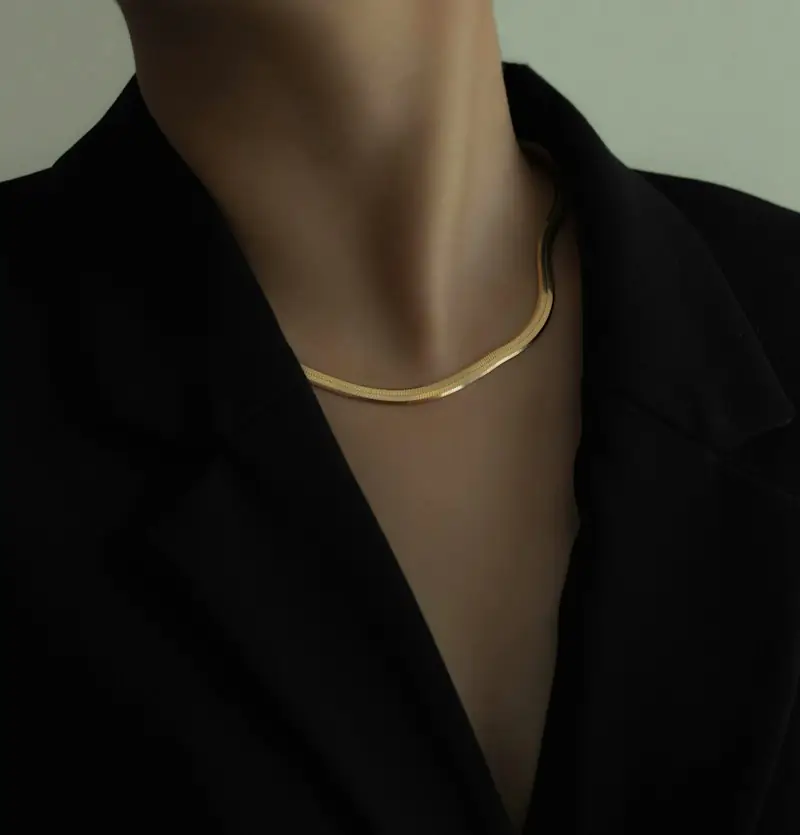 Fine gold chain necklace on a woman in a black blazer