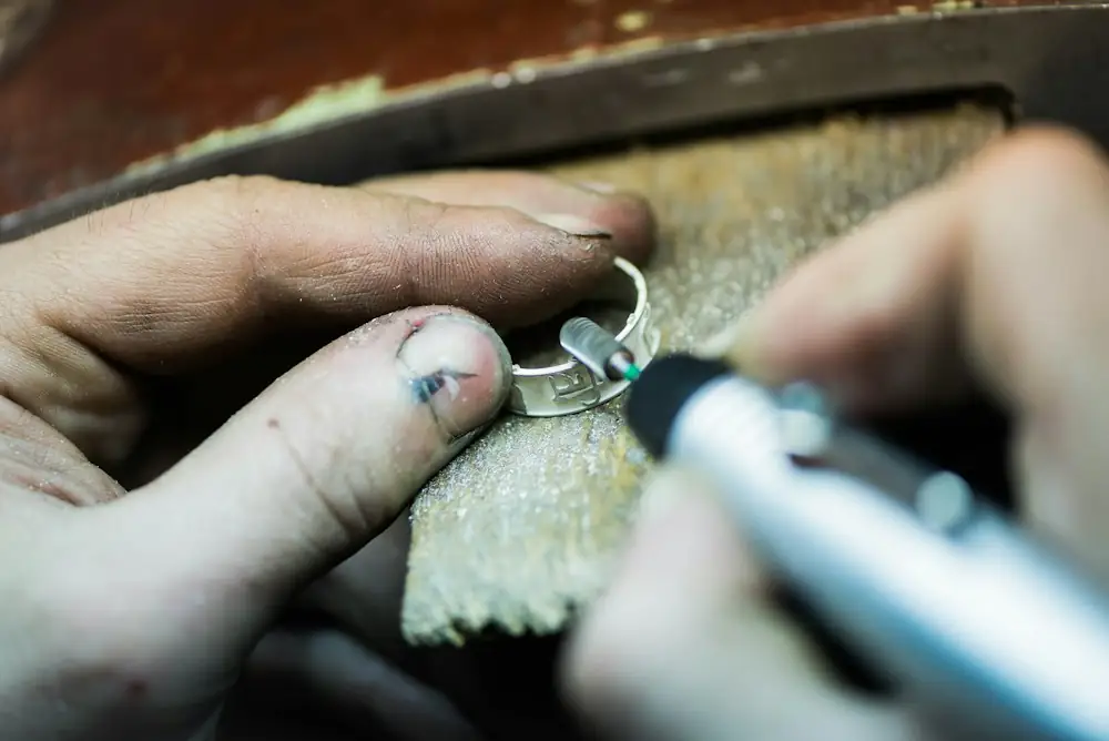 Hands filing a silver ring with a rotary tool