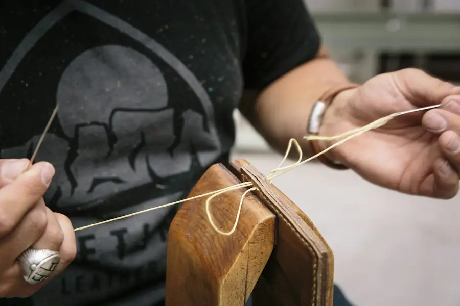 Hands hand-stitching a leather piece in a clamp