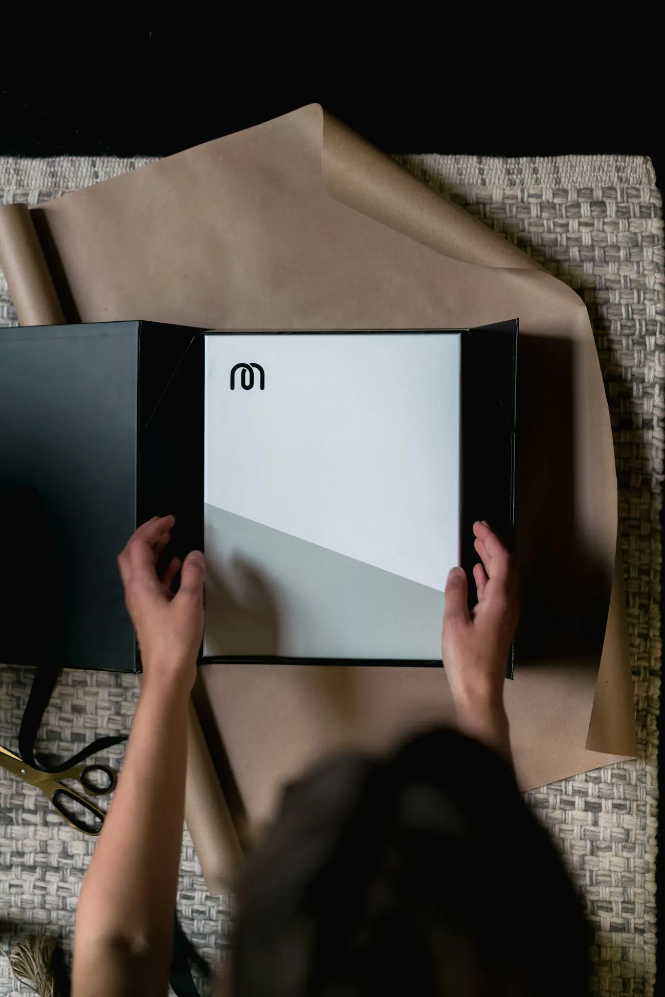 Hands opening a black retail box lined with brown paper
