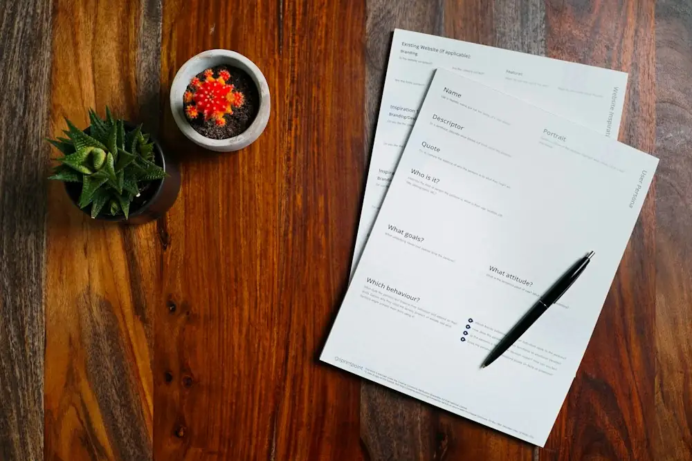 A project brief form and a pen on a wooden desk