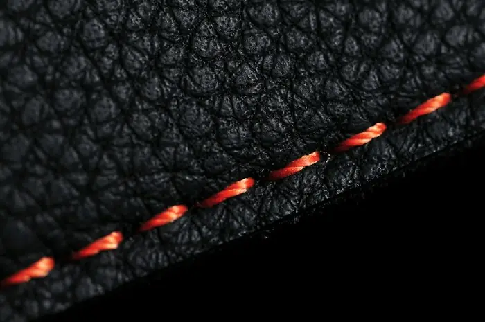 Orange stitching along the edge of black leather